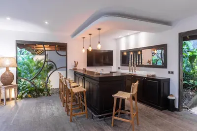 an open kitchen with a bar with wooden chairs at Large 6-Bedroom Private Villa with Pool for Groups & Families - Umalas in Kerobokan