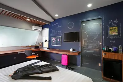 a room with a bed and a desk and a screen at Berry Biz Hotel Sunset Road in Seminyak