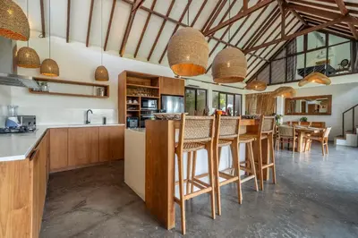 a kitchen with wooden cabinets and a bar with stools at Villa Tarita Canggu in Kerobokan