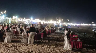 a large group of people sitting at tables at a beach at night at Lavanda guesthouse/homestay in Jimbaran