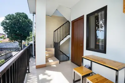 a small balcony with a wooden bench and stairs at K Hostel Seminyak in Seminyak