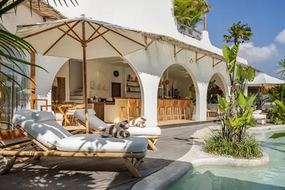 a pool with chairs and an umbrella next to a house at Villa Lagertha by Optimum Bali Villas in Kerobokan