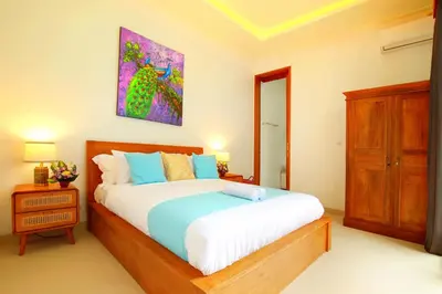 a bedroom with a bed and a painting on the wall at Villa Noam By Bali Asia Villa in Jimbaran