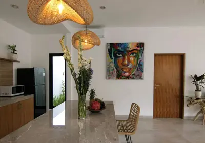 a kitchen with a table with a painting on the wall at VILLA NIKOLE in Seminyak