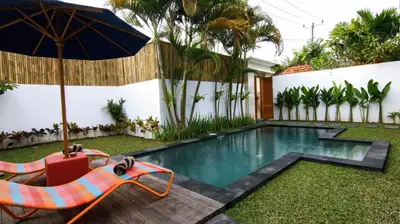a swimming pool with a chair and an umbrella at VILLA NIKOLE in Seminyak