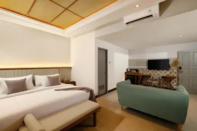 a bedroom with a bed and a green chair at The Mahata in Legian
