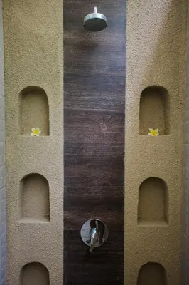 a bathroom with a wall with arches on it at Donguri House Bali in Jimbaran