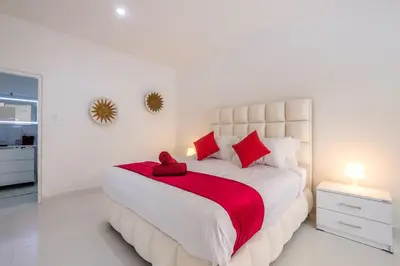 a white bedroom with a large bed with red pillows at Luxury minimalist villa White Angel in Seminyak, sleeps 21 people in total in Seminyak