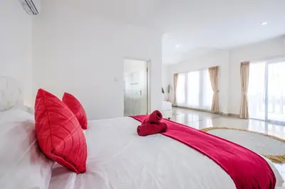 a bedroom with red pillows on a white bed at Luxury minimalist villa White Angel in Seminyak, sleeps 21 people in total in Seminyak