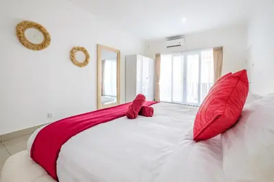 a white bed with two red pillows on it at Luxury minimalist villa White Angel in Seminyak, sleeps 21 people in total in Seminyak