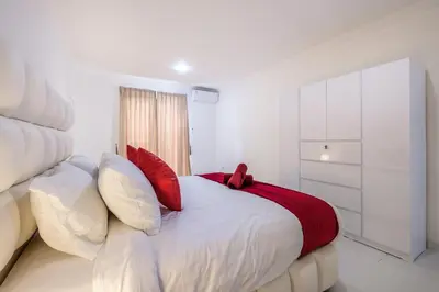 a white bedroom with a large bed with red pillows at Luxury minimalist villa White Angel in Seminyak, sleeps 21 people in total in Seminyak