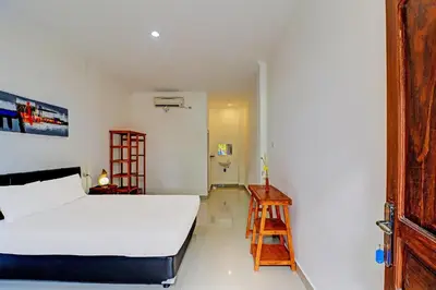 a bedroom with a white bed and a wooden ladder at Capital O 92094 Hotel Kertha in Pesanggaran