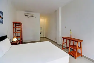 a bedroom with a white bed and a wooden shelf at Capital O 92094 Hotel Kertha in Pesanggaran