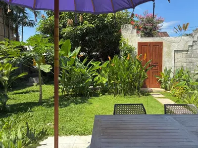 a table with a purple umbrella and two chairs at Villa Abhista Seminyak in Seminyak
