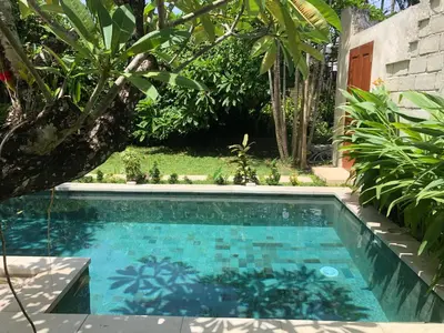 a swimming pool in the middle of a garden at Villa Abhista Seminyak in Seminyak