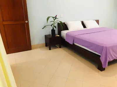 a bedroom with a bed with purple sheets and a plant at Villa Abhista Seminyak in Seminyak