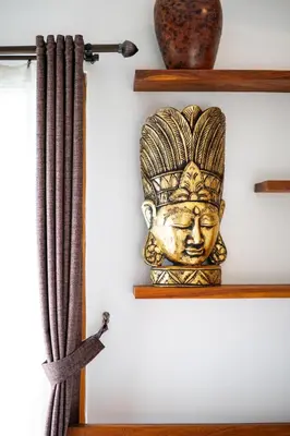 a wooden statue on a shelf next to a curtain at Malinda Villa Seminyak in Seminyak