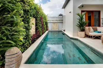 a swimming pool in the backyard of a house with plants at Malinda Villa Seminyak in Seminyak