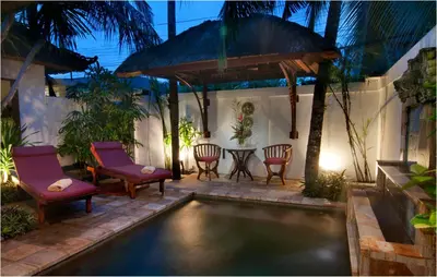 a swimming pool in a backyard with chairs and a table at 6BR Villa Sensel - Minggu Villas Seminyak in Seminyak