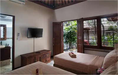 a bedroom with two beds and a flat screen tv at 6BR Villa Sensel - Minggu Villas Seminyak in Seminyak