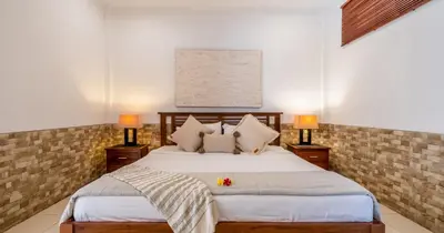a bedroom with a large bed with two lamps at Taman Hijau Villa by iBali Management in Kerobokan