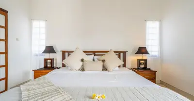 a bedroom with a white bed with two lamps at Taman Hijau Villa by iBali Management in Kerobokan