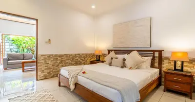 a bedroom with a bed and a couch and a window at Taman Hijau Villa by iBali Management in Kerobokan
