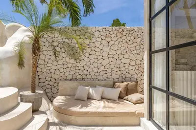 a couch sitting on a patio next to a stone wall at Private Pool Villa Bocami Suites- 1 by OriVista in Kerobokan