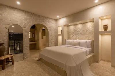 a bedroom with a large bed and a stone wall at Private Pool Villa Bocami Suites- 1 by OriVista in Kerobokan