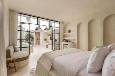 a white bedroom with a large bed and a chair at Private Pool Villa Bocami Suites- 2 by OriVista in Kerobokan