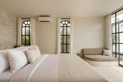 a bedroom with a large white bed and a chair at Private Pool Villa Bocami Suites- 2 by OriVista in Kerobokan