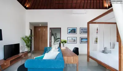 a living room with a blue couch and a tv at 8BR Villa Mason - Minggu Villas in Seminyak