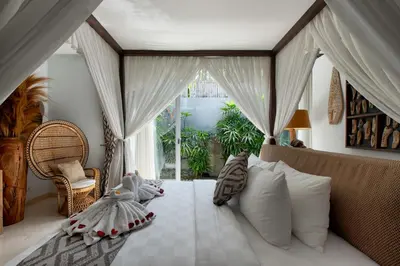 a bedroom with a bed with pillows and a window at Villa Deh Simba at Seminyak Aramanis in Seminyak