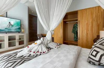 a bedroom with a bed with white sheets and a tv at Villa Deh Simba at Seminyak Aramanis in Seminyak