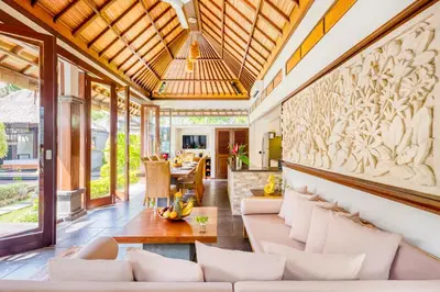 an outdoor living room with white furniture and a wall with a mural at Villa Jalamati in Seminyak