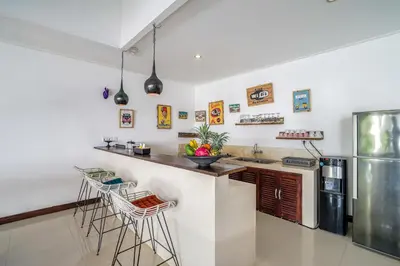 a kitchen with a counter and a refrigerator at Villa Art Gecko, 2BR private haven in Heart of Batu Belig, Seminyak in Canggu