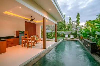 an infinity pool in a villa with a kitchen and dining room at Kahayana Seminyak Villa in Seminyak