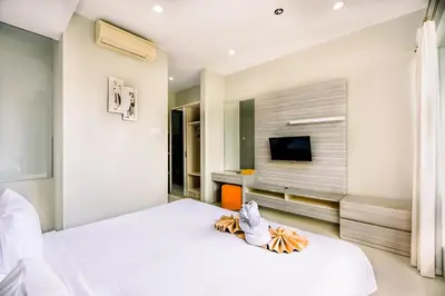 a white bedroom with a bed and a tv at Abisha Villa Jimbaran in Jimbaran