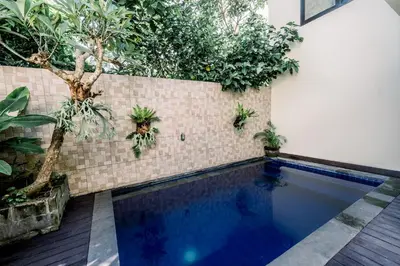 a swimming pool with plants on a wall at Abisha Villa Jimbaran in Jimbaran