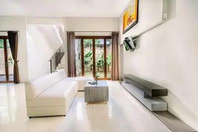 a living room with a white couch and a tv at Abisha Villa Jimbaran in Jimbaran