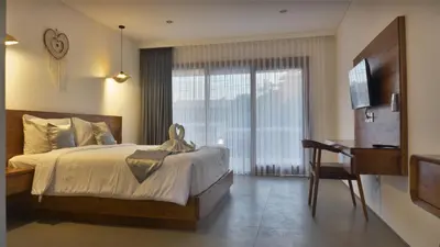 a bedroom with a bed and a desk and a television at Kedin's Inn in Denpasar