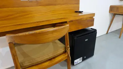 a wooden desk with a chair next to a computer at Kedin's Inn in Denpasar