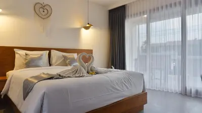 a bedroom with a bed with white sheets and a window at Kedin's Inn in Denpasar
