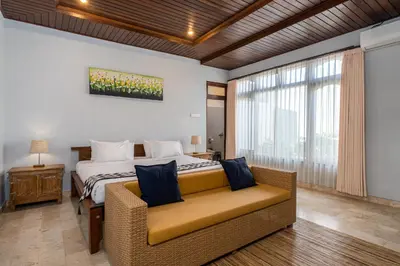 a bedroom with a bed and a couch and a window at Villa Kori Bali Kubu, 9 people maximum, close to Seminyak Beach in Seminyak