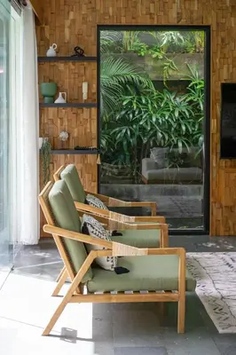 a green chair sitting on a porch with a painting at Villa Suvitha by Villa Finder in Seminyak