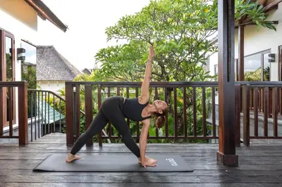 a woman doing a yoga pose on a yoga mat at Villa Suvitha by Villa Finder in Seminyak