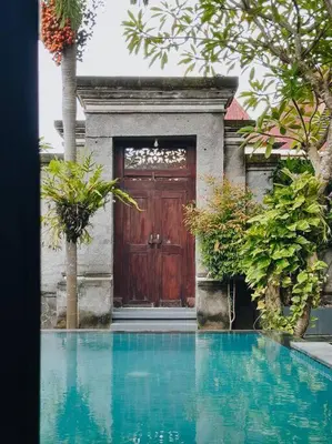 a wooden door with a pool of water in front of a house at Villa Sriwedari - Seminyak in Seminyak