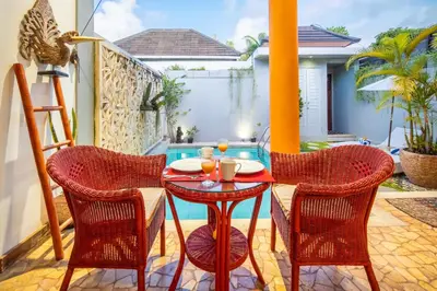 a patio with a table and chairs and a pool at Villa Lollie Seminyak in Seminyak