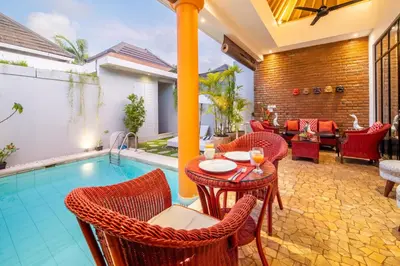 a patio with a table and chairs next to a swimming pool at Villa Lollie Seminyak in Seminyak