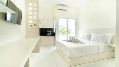 a white bedroom with a bed and a kitchen at The Axara Bali Managed by ARM Hospitality in Nusa Dua